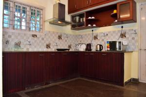 蓬蒂切里Revive Inn Pondy - Rooms & Villa的厨房配有深色木橱柜和微波炉