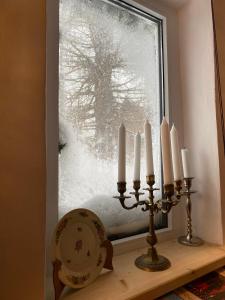 布什泰尼Bohemian Chalet的一个带蜡烛的窗户,放在一个有雪盖的窗户的架子上