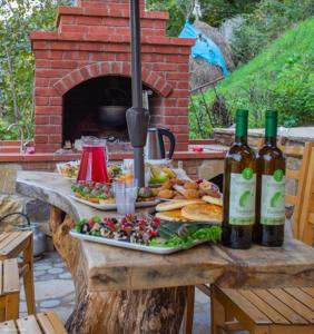 ShuakheviGuest House Okropilauri的一张桌子,上面放着两盘食物和瓶装葡萄酒