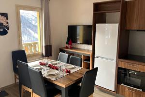 伊索拉2000Refuge des Vues Alpines Isola 2000的厨房配有桌椅和白色冰箱。