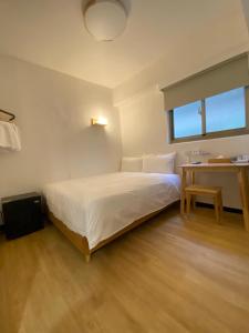台北宏洲旅社HZ Hotel的卧室配有白色的床和书桌