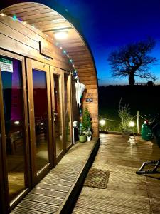 格拉斯哥FINN VILLAGE – Loch Lomond Luxury Lodges with All Year-Round Hot Tubs and Gazebos的一座晚上有木甲板的建筑