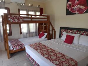 日惹Rosella Cottage - Homestay - Kitchen Yogyakarta的一间卧室配有两张双层床和红色枕头