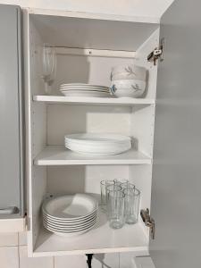 瓦萨Vaasa homestay的一间白色厨房,配以盘子和玻璃杯,配以餐具