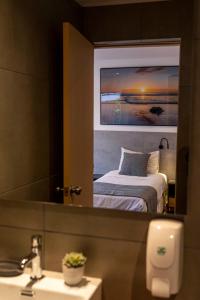 埃斯特角城TAS D VIAJE Suites - Hostel Boutique的浴室设有镜子、一张床和一个水槽