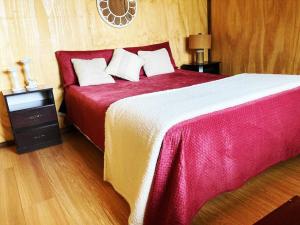拉埃斯梅拉达Cabaña 2 dormitorios cerca de Mágica Playa!的一间卧室配有一张带红色和白色床单的大床