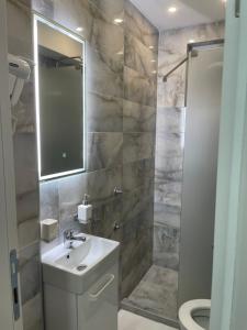 萨拉热窝Inaya Apartman的一间带水槽、镜子和淋浴的浴室
