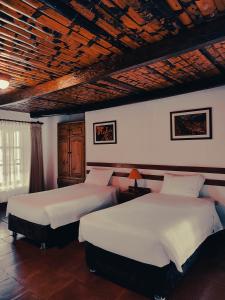 查查波亚斯Hotel Fundo Achamaqui的一间卧室设有两张床和木制天花板