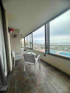 康康Costa de Montemar Full Vista al mar的客房设有桌椅和大窗户。