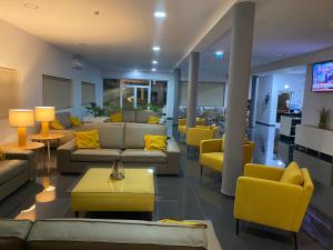 内拉什JP HOUSE的大堂配有沙发、桌子和黄色椅子