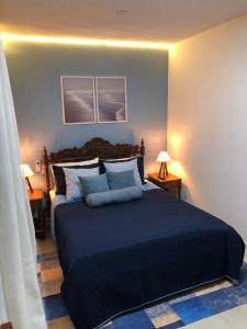 卡波布里奥Suíte Verão na Praia的一间卧室配有一张带蓝色枕头的大床