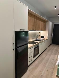 阿格里尼翁Olive-Luxury apartment in agrinio的厨房配有黑冰箱和白色橱柜。