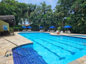 圣劳伦斯海滨Flat na Riviera de São Lourenço com serviço de hotelaria的度假村的游泳池,配有蓝色遮阳伞