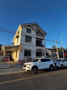大叻Ánh Vân Villa hotel的两辆汽车停在白色建筑前面