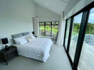 陶朗加Guesthouse @ Te Puna的卧室设有白色的床和大窗户