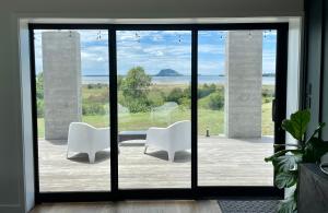 陶朗加Guesthouse @ Te Puna的滑动玻璃门前两把白色椅子