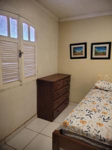 托鲁斯Perobas beach house的一间卧室配有一张床、一个梳妆台和两个窗户。
