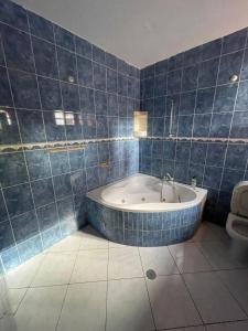 普拉亚Casa Cor de Rosa的蓝色瓷砖浴室设有浴缸和卫生间