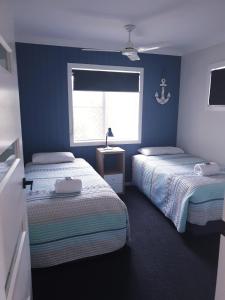 赫维湾Lisianna Apartments的配有两张床铺的蓝色墙壁和窗户