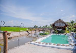Ba RiaLUA Farmstay的一个带茅草小屋和游泳池的游泳池