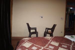 卡索尔Apple Garden Katagla Kasol的两把椅子坐在一个房间里的床边