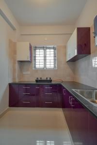 班加罗尔HomeSlice Whitefield - 1BHK/ 2BHK Apartment/ Studio Room的厨房配有紫色橱柜和水槽