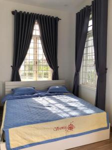 顺化Nhat Long Homestay的卧室内的一张床位,设有两个窗户