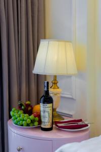 海防Le Haute Hotel Hai Phong的一张桌子上摆放着一瓶葡萄酒,放着一盏灯