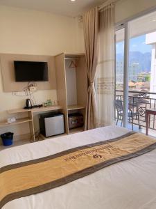 万荣Galaxy VangVieng Hotel的一间卧室设有一张带电视的床和一个阳台。