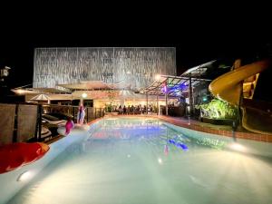 罗勇Xanadu Hotel Utapao的一座大型游泳池,晚上与大楼相连