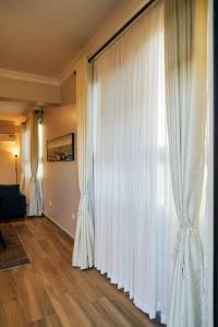 阿鲁沙Westwood Residences的客厅配有白色窗帘和硬木地板