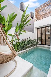 坎古Besso Villa by Hombali的别墅 - 带带椅子和植物的游泳池