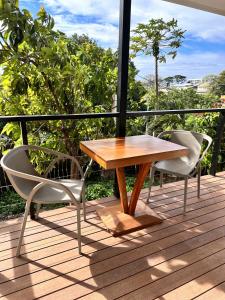 帕皮提Ononui Lodge Airport, Ocean-View, Private Bathroom and Balcony, Free WiFi and Parking, On-Site Car Rental的甲板上的一张木桌和两把椅子