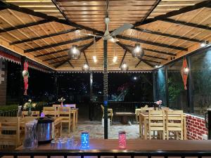 奈尼塔尔Sangita Resorts的餐厅设有吊扇和木桌及椅子
