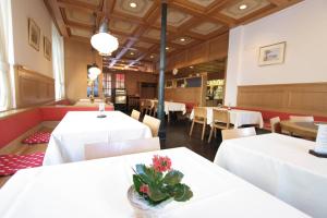 格拉鲁斯Hotel Post Glarnerhof的用餐室配有白色的桌椅和鲜花。