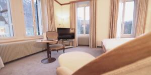 格拉鲁斯Hotel Post Glarnerhof的酒店客房配有一张床、一把椅子和一张书桌