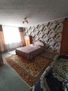 卡拉甘达Уютная квартира в центре города的一间卧室,配有一张床,墙上有地毯