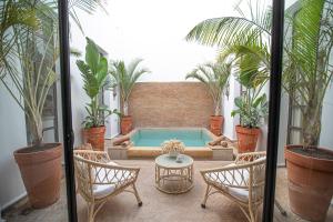 马拉喀什Riad Coconut的庭院设有游泳池、椅子和植物