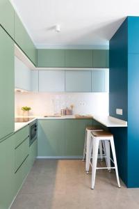 马德里Estudio moderno y acogedor en Madrid Rio nº3的厨房配有蓝色和绿色的橱柜和凳子