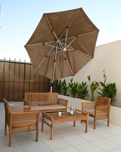 吉达2 Bedroom Apartment in Jeddah的三把椅子和一张带大伞的桌子