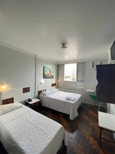 图巴朗Oscar Palace Hotel - SOB NOVA GESTÃO的一间卧室配有两张床和一台平面电视