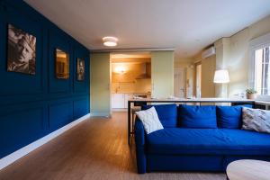 塞维利亚森特拉尔套房公寓的一间带蓝色沙发的客厅和一间厨房