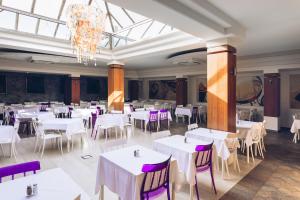 布德瓦斯洛文尼亚广场酒店的一间设有白色桌子和紫色椅子的用餐室