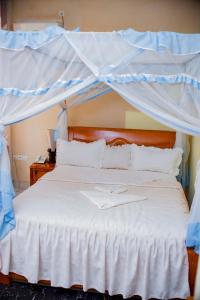 布琼布拉Tigers's apartment Hotel的一间卧室配有一张带天蓬的白色床
