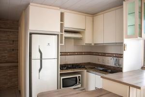 弗洛里亚诺波利斯Otimo apto 9 min do aeroporto em Florianopolis SC的厨房配有白色橱柜和冰箱。