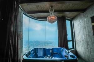 朱尼耶海湾精品酒店的窗户前带蓝色浴缸的浴室