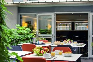 巴黎贝朗布阿城市酒店的一间餐厅配有桌椅,提供食物