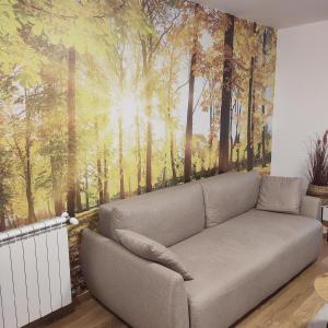 Novi BeogradDuki1的客厅的沙发,带有森林壁画