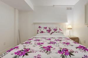 惠特比Comfortable Whitby 2 Bedroom Lower Suite的一间卧室,床上有紫色鲜花