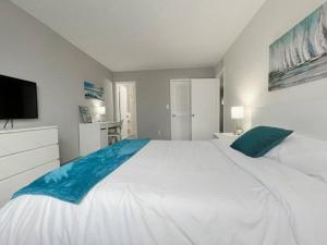 圣徒皮特海滩Beautiful 2 Bed Beach Condo With DOCK - Walk Everywhere!的卧室配有一张白色大床和一台平面电视。